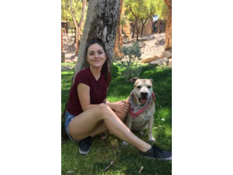 Woman sitting with her dog outdoors.