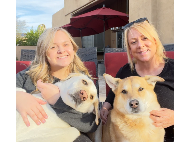 Two women with their dogs outdoors.