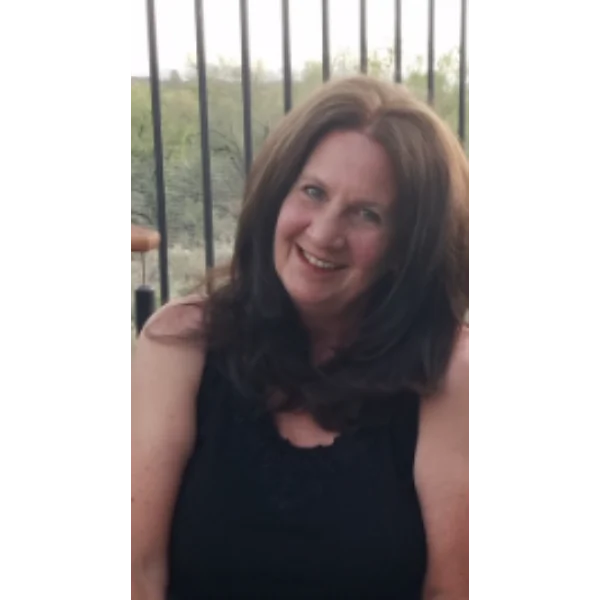 Smiling woman with brown hair outdoors.