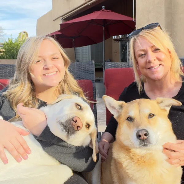 Two women with their dogs outdoors.