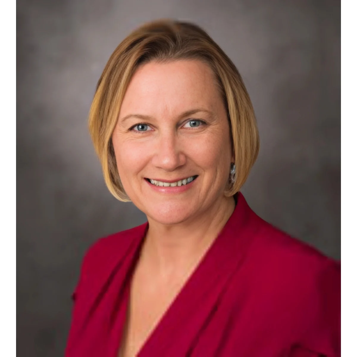 Here's an alt tag for the image: Smiling woman in red blazer.